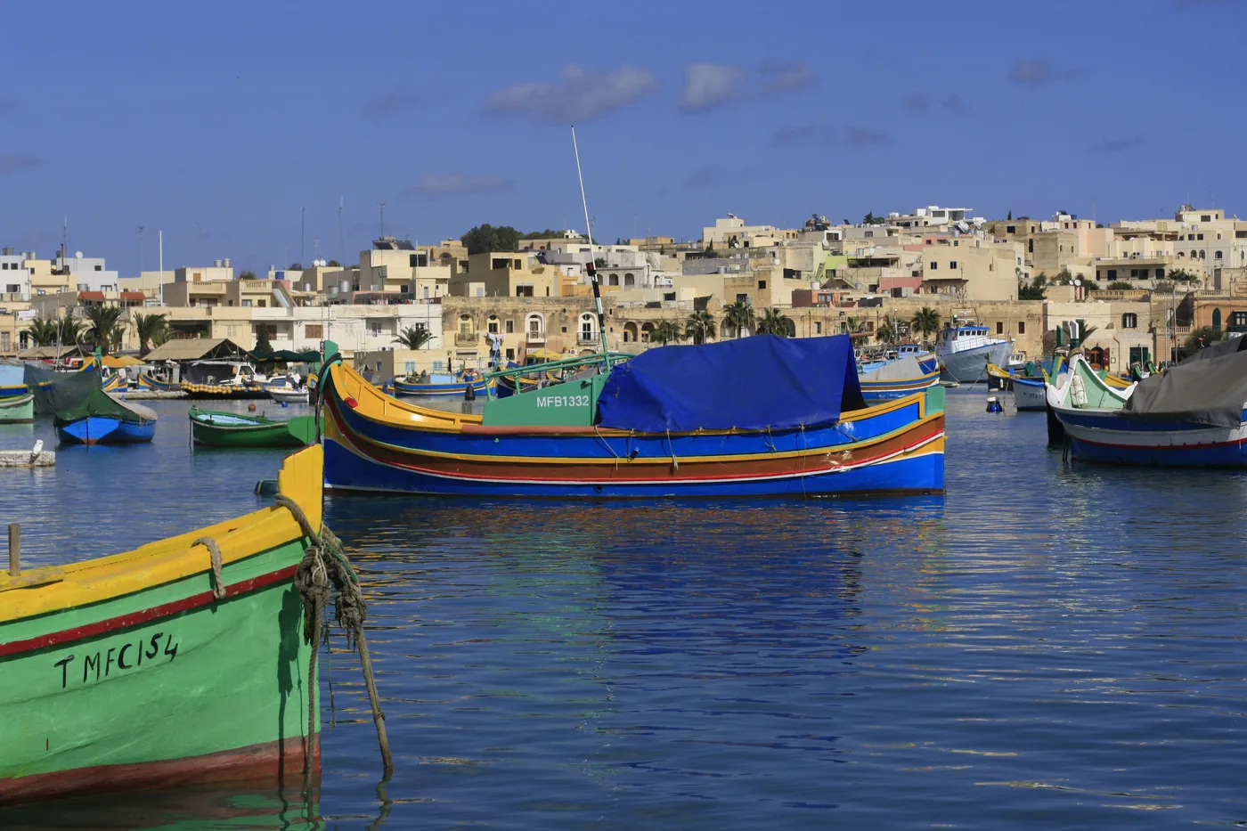 Colourful luzzu fishing boats moored in the harbour of Marsaxlokk